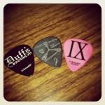 2 Ice Nine Kills guitar picks, JD's custom in the center, a Duffs Brooklyn guitar pick on the left and a general IX guitar pick. 